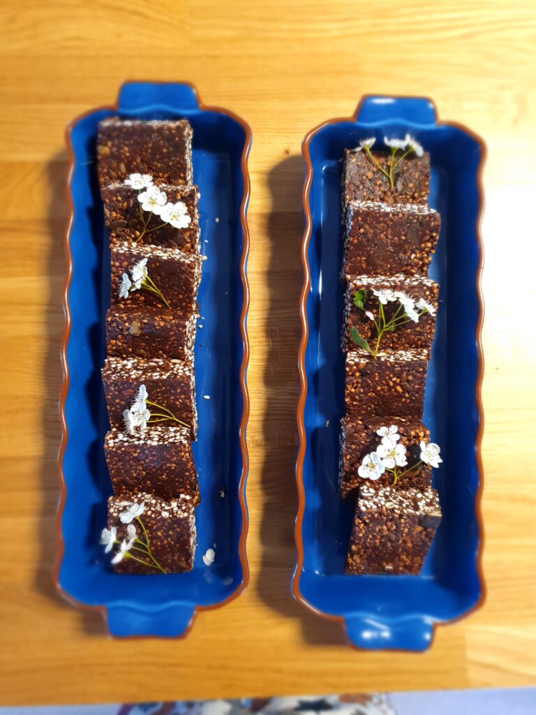 Vegan, gluten-free puffed quinoa, seeds, tahini and chocolate bars with hawthorn flowers